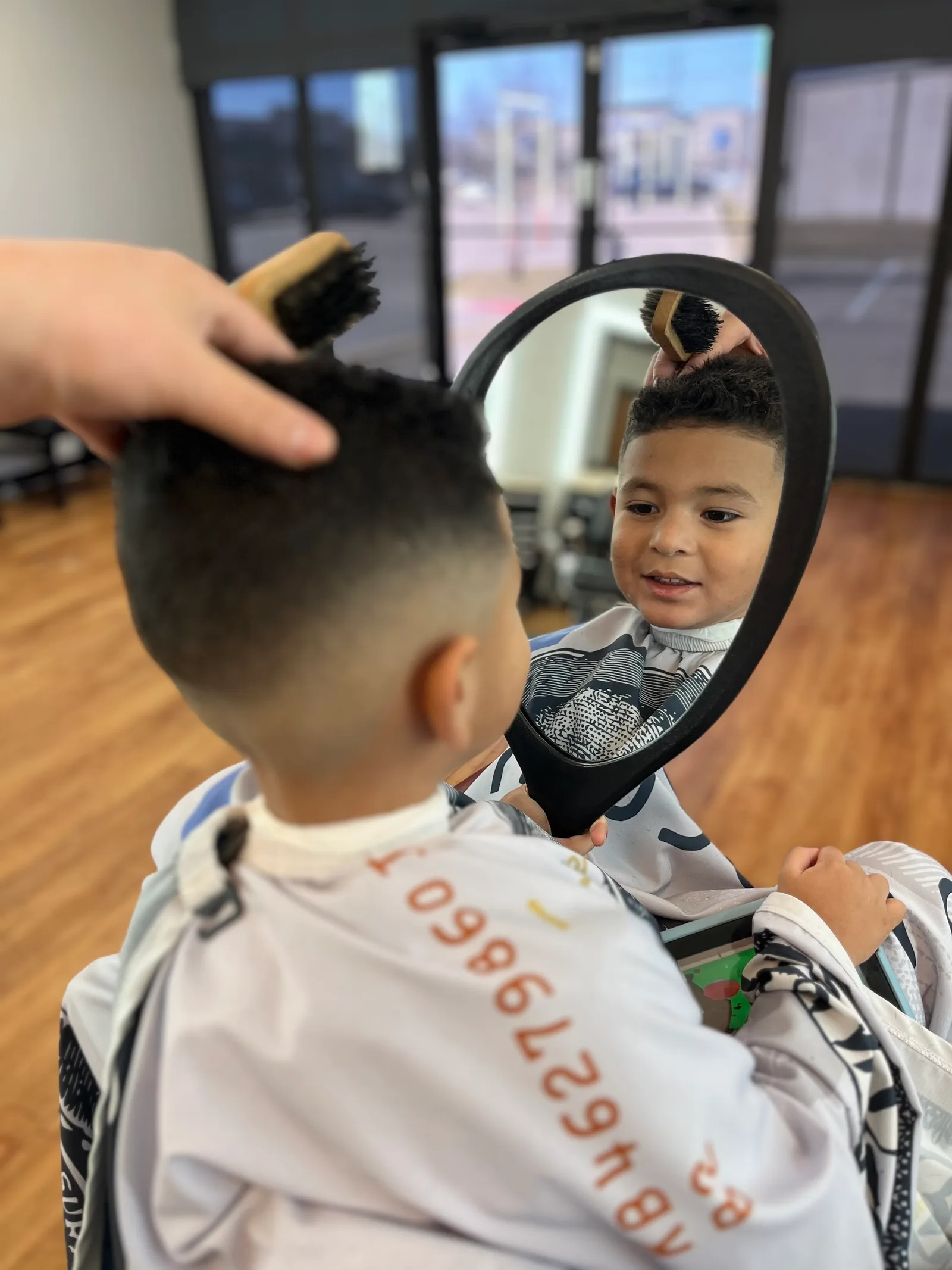 A kid checking his first fade in the mirror